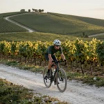 Cycliste sur un velo gravel roulant sur un chemin crayeux entre les vignes de Champagne